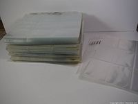 Stack of used clear plastic binder sheets showing varying conditions, some sheets appear worn or discolored.