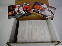 Open box filled with 200 hockey cards from the 2010-11 Upper Deck Series 1 set with several cards spread on top showing players in NHL uniforms including Sidney Crosby.