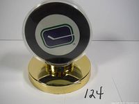 Front view of vintage Vancouver Canucks puck in clear acrylic case on gold display stand showing the Canucks logo