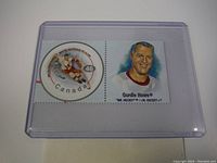 Close-up photo of the 2000 Canada Post Gordie Howe stamp in a clear plastic protective case, showing the hockey player image and a portrait of Gordie Howe.