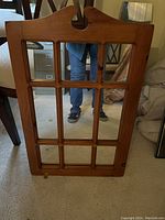 Front view of the pine mirror showing rectangular wooden frame divided into 9 windowpane sections with carved top detail.