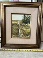 Framed oil painting with visible measuring tape showing frame dimensions, a weathered post in a marshland setting.