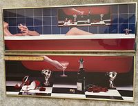 Photo showing two vintage 1980s bathtub prints framed and placed side by side. Upper print features a reclining figure in red bathtub with blue tile background. Lower print shows red bathtub end with champagne bottle, glasses, red shoes, and red roses on black and white checkered floor.
