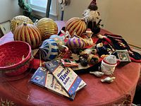Photo shows large red and gold glitter striped balls along with various ornaments, figurines, and holiday decor.