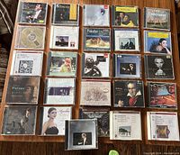Photo of 26 classical music CDs laid out on a wooden surface, showing full covers and titles