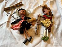 Two vintage 1970s marionette puppets laid on fabric background, featuring Wicked Witch and Gretel in detailed costumes with strings and wooden control bars.