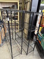 Pair of black metal wire shelving racks side by side in garage environment showing size and condition.