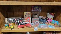 Full lot view displaying all items on wood shelf including toys, playing cards, and Hello Kitty collectibles