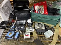 Lot contents including cameras, lenses, bags and accessories on a wire shelf.