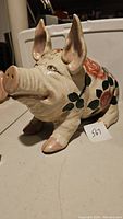 Left side angled view showing cabbage rose painted decoration on white ceramic pig figurine with large upright ears and detailed facial features.