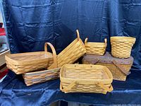 Full grouping of seven vintage Longaberger wooden baskets shown from front, various sizes and shapes