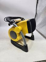 Side view of Stanley air mover fan showing yellow body and black air outlet grille with power cord wrapped around the handle.