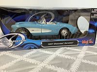 Front-side view of 1957 Chevrolet Corvette die-cast model in original packaging showing details and colors.