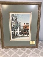 Front view of a framed print showing a French street scene with a bronze-tone decorative frame and gray matting.