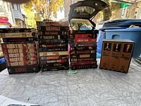 Photo of a large collection of VHS movies stacked outside showing titles such as Die Hard 2, Rocky series, Speed, Scarface, Child's Play, and others.