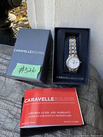 Bulova Caravelle watch in original black box alongside the owner's guide and warranty booklet on outdoor surface.
