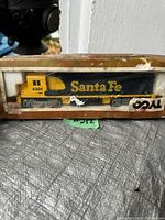 Vintage HO scale Santa Fe train engine with original box showing visible damage and wear.
