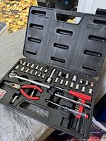Open plastic carrying case showing ratchet, sockets, pliers, and screwdrivers