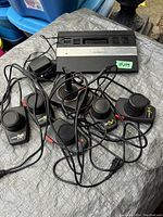 Atari 2600 console with six joystick controllers and power supply laid out, cables tangled.
