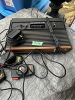 Overview of Atari console with cartridge slot, switches, power adapter on top of console, and Denver post-it note with lot number.