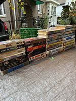 Photo showing the full lot of VHS movies stacked in rows outdoors, showcasing the quantity and visible title spines.