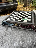 Chess board with dragon heads on corners, angled side view showing red and blue dragons and checkerboard game surface.