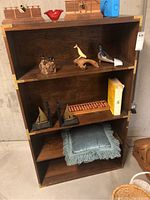 Front view of wooden bookcase with various decorative items on shelves, showing the overall size and condition.