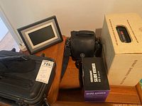 Photo showing digital photo frame, black Ambico Classic case, Kodak Carousel projector box, and boxed Medalight Slide Viewer SV-3