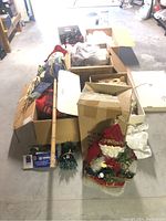 Photo showing multiple cardboard boxes and items on the floor including large Santa figure and boxes of Christmas decorations