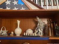 Shelf with folded flag case and assortment of figurines and vases