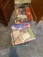 Stack of assorted puzzles showing several puzzle boxes including one with a Christmas market scene in France.