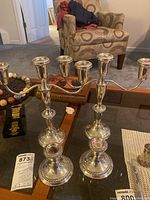 Overview of two three-arm candelabras and two single candlesticks on table