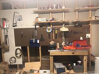 General view showing hammers, screwdrivers, hack saw on pegboard, drill bit case and tool box on workbench, extension cords coiled on pegboard
