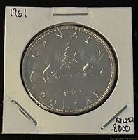 Obverse side showing sailing ship and inscription 'CANADA 1961 DOLLAR' in white cardboard holder with markings.