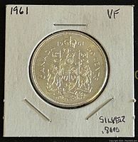 Obverse side of the 1961 Canadian silver 50 cent coin showing the Canadian Coat of Arms and inscription with date and denomination.