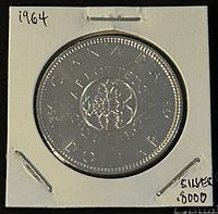 Reverse side of a 1964 Canadian silver dollar coin showing the Canadian Centennial floral emblem with inscriptions 'CANADA', '1864-1964', and 'DOLLAR'. Coin held in a white cardboard and plastic holder.