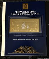 Blue presentation card labeled with 'The World's First Gold & Silver Banknotes' and the banknote mounted on front showing gold foil with embossed ship images.