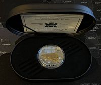 Full view of silver proof coin in black presentation case with certificate.