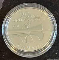 Obverse side of the coin showing two paddlers in a canoe and inscriptions indicating denomination, year, purity, and country.