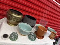 Wide shot of all planters and flower holders on display, showing bronze, pottery, terra-cotta, and glass items
