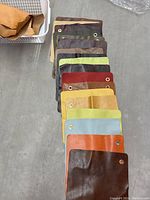 Stack of assorted pigmented leather swatches arranged in a neat pile showing different colors and the metal grommets on each.