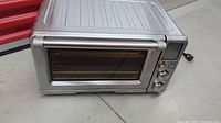 Front view of stainless steel toaster oven on floor.