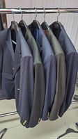 Five men's blazers hanging on a rack, showing side and shoulders, various colors and sizes