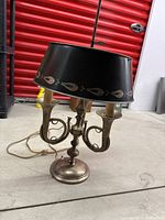 Photo showing front view of the metal table lamp with curved trumpet-shaped arms and black lampshade.