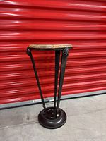 Full view of round marble and metal side table with lion emblems on the side, shown against a red background.