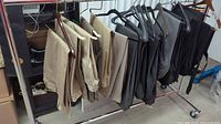 Wide view of nine pairs of men's dress pants and slacks hanging on a rack showing colors and styles