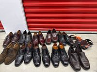 Wide view of 13 pairs of men's leather shoes in brown and black including oxfords, wingtips, loafers, and slip-ons displayed together
