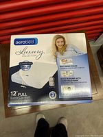Front and top of the box showing AeroBed Luxury Collection full size mattress with guarantee of no leaks and built-in pump with hand-held wand