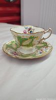 Photo showing the vintage bone china teacup and matching saucer with floral design and gold accents, highlighting the ornate handle and edges.