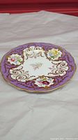 Top view showing the decorative floral and gold pattern details on the plate with purple border.